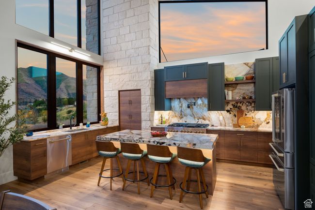 Kitchen with stainless steel appliances, light stone countertops, light wood finished floors, and a breakfast bar | Image 26