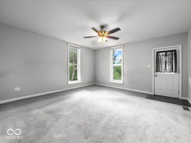 empty room with dark carpet and a ceiling fan | Image 4