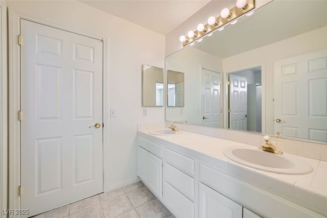 Bathroom with double vanity, tile patterned flooring, a sink, and baseboards | Image 48