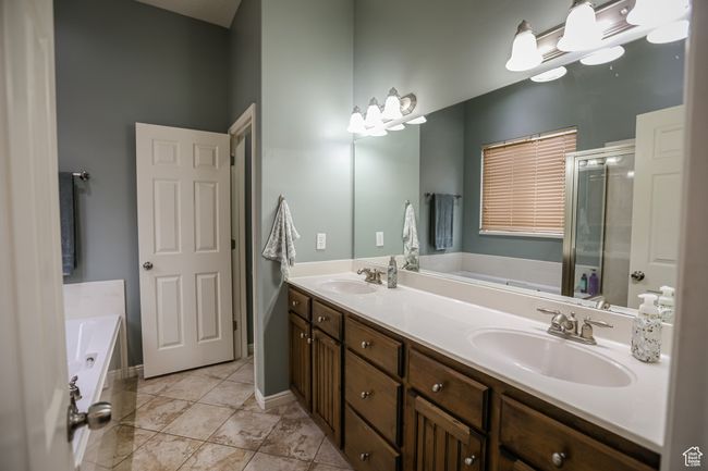 Full bathroom with double vanity, a bath, a stall shower, tile patterned floors, and baseboards | Image 24