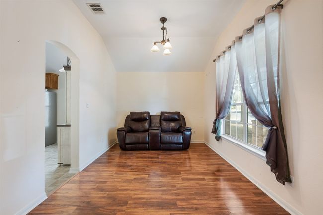 Living area featuring wood finished floors, visible vents, baseboards, lofted ceiling, and arched walkways | Image 9