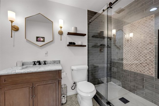 Bathroom featuring baseboards, toilet, a stall shower, and marble vanity | Image 17