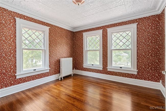 Bedroom featuring radiator, healthy amount of natural light, hardwood floors, ornamental molding, and baseboards | Image 28