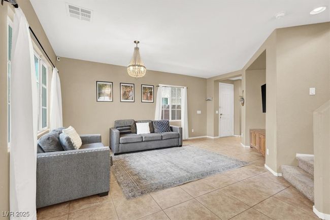 Living area with light tile patterned flooring, stairway, baseboards, and a chandelier | Image 5