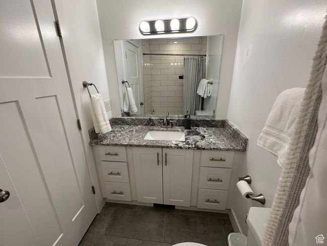 Bathroom with toilet, vanity, tiled shower, and tile patterned floors | Image 11