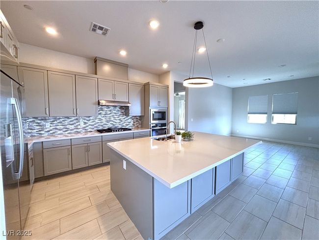 Kitchen with gray cabinets, an island with sink, appliances with stainless steel finishes, under cabinet range hood, and visible vents | Image 13