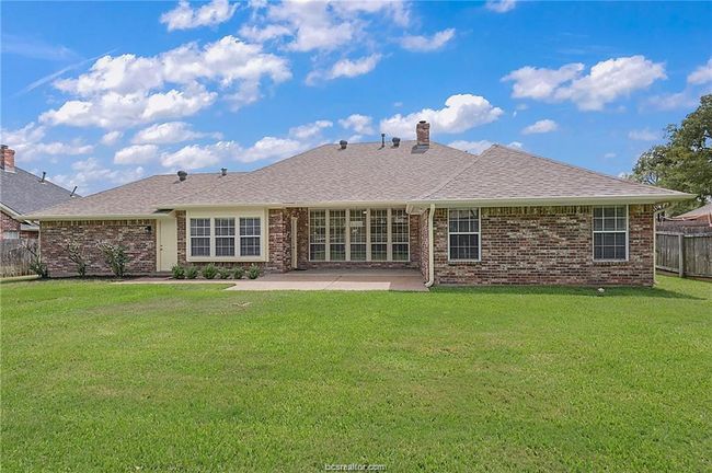 Rear view of property featuring a patio, brick siding, a chimney, and roof with shingles | Image 19