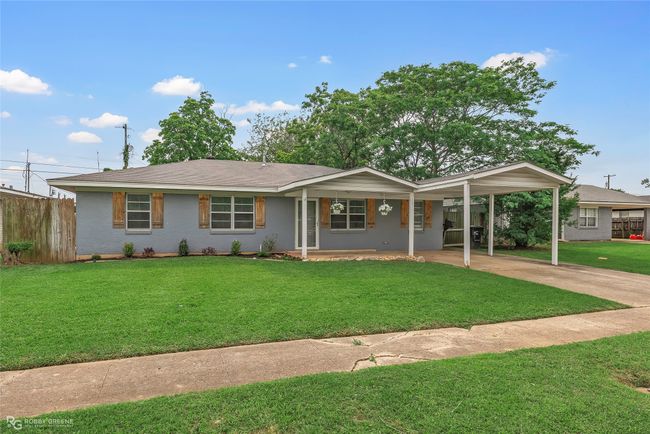 Ranch-style home featuring a front yard, covered porch, driveway, a carport, and fence | Image 23