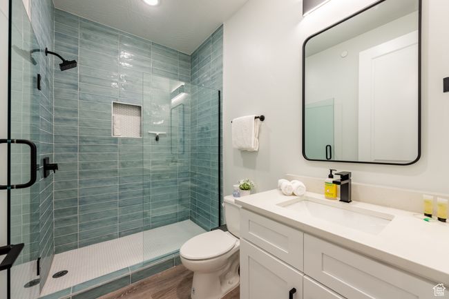 Bathroom with toilet, vanity, a shower with door, and hardwood / wood-style floors | Image 35