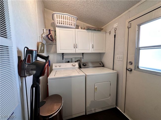 Laundry room featuring a textured ceiling, cabinet space, washing machine and clothes dryer, and a heating unit | Image 17