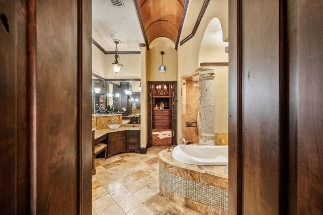Full bathroom featuring a jacuzzi tub, vanity, ornamental molding, and stone floors | Image 24
