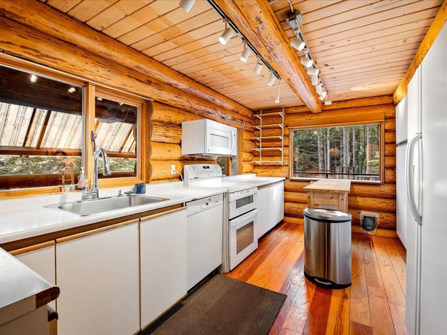 Kitchen featuring light countertops, white appliances, white cabinetry, and a sink | Image 8