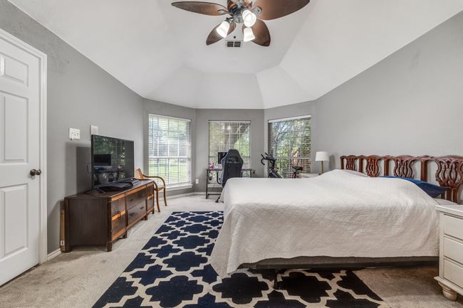 Bedroom with light colored carpet, vaulted ceiling, ceiling fan, and baseboards | Image 26