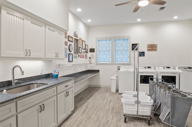 Kitchen featuring washer and clothes dryer, visible vents, light wood-style flooring, a sink, and dark stone countertops | Image 23