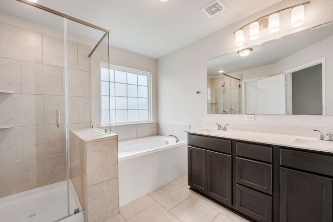 Luxury primary bath with double vanity, separate tub and shower, and natural light. | Image 18