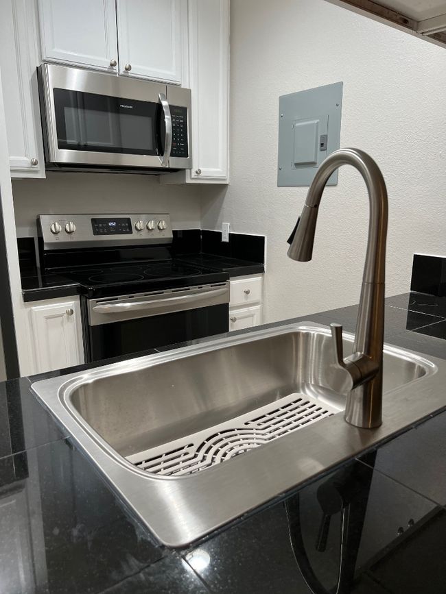 Room details with white cabinets, electric panel, and stove | Image 8