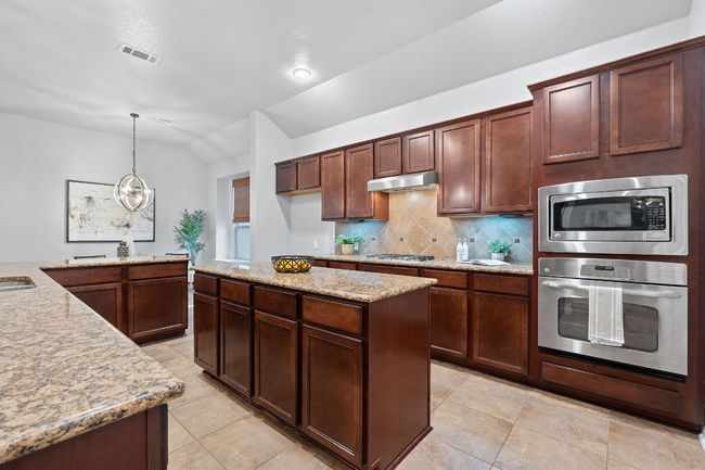 Kitchen with appliances with stainless steel appliances, tasteful backsplash, under cabinet range hood & vaulted ceiling | Image 13