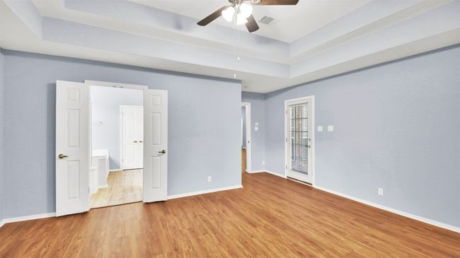 Master bedroom with vinyl plank floors, a raised ceiling, and ceiling fan | Image 27