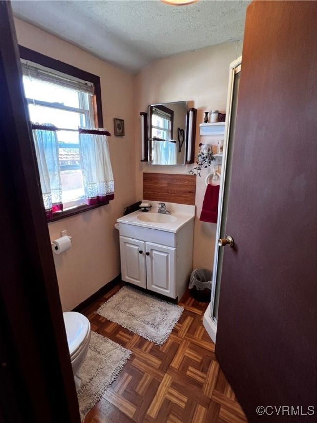 Bathroom with toilet, a shower with door, vanity, a textured ceiling, and parquet flooring | Image 26