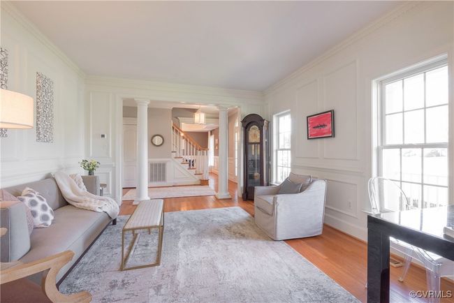 Living room featuring a decorative wall, crown molding, ornate columns, wood finished floors, and stairs | Image 9