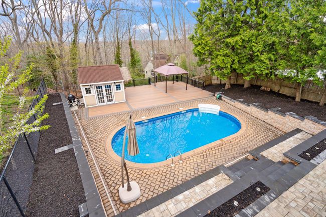 View of pool with a wooden deck, a fenced in pool, a fenced backyard, and an outdoor structure | Image 45