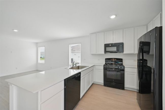 Kitchen featuring black appliances, a peninsula, white cabinets, light countertops, and recessed lighting | Image 8