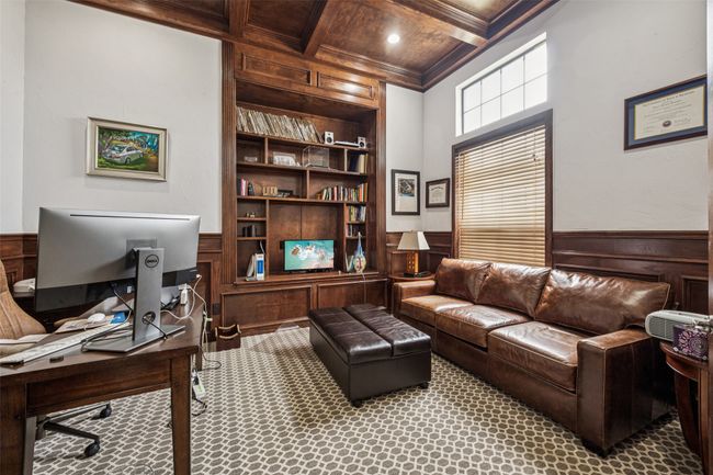 Carpeted home office featuring built in shelves, wood walls, ornamental molding, a wooden ceiling with exposed beams, and coffered ceiling | Image 10