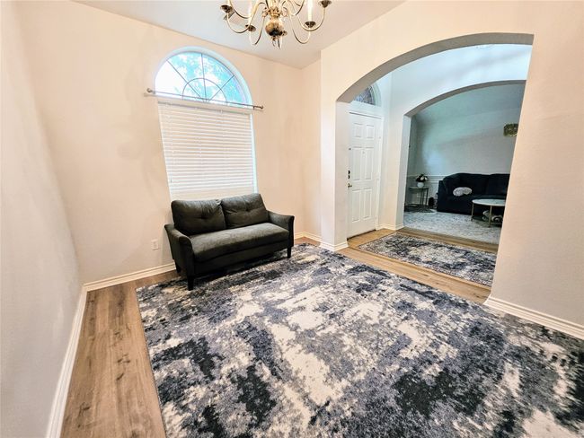 Sitting room with arched walkways, wood finished floors, and a chandelier | Image 16