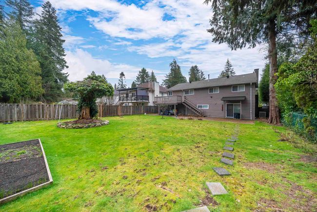 View of yard featuring a fenced backyard, a wooden deck, stairway, and a vegetable garden | Image 6