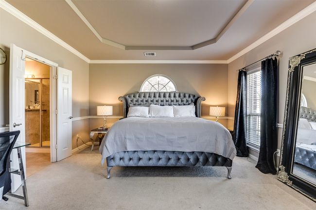 Bedroom with connected bathroom, light colored carpet, a raised ceiling, and multiple windows | Image 26