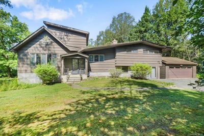 View of front facade with a sunroom, a front yard, and a garage | Image 1