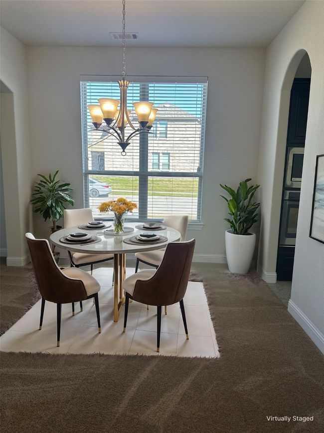 Dining space with a chandelier, arched walkways, light colored carpet, visible vents, and baseboards | Image 4