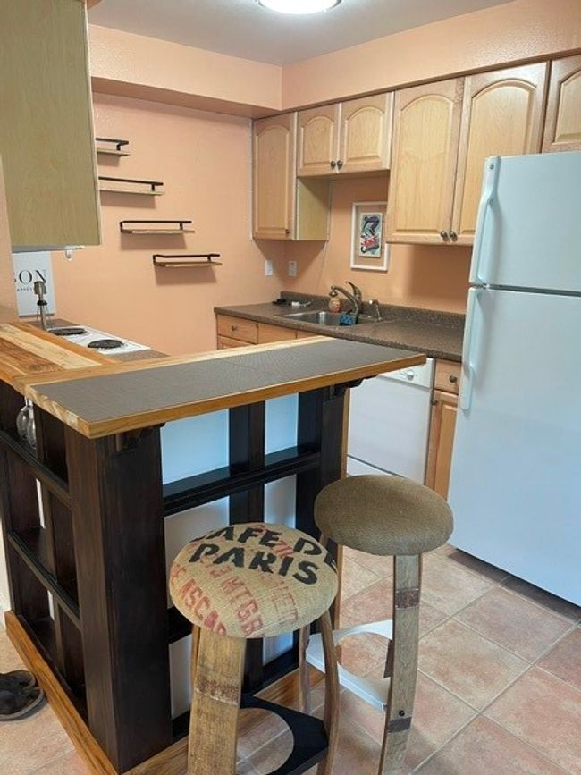 Kitchen featuring dark countertops, light brown cabinets, refrigerator, and a sink | Image 17