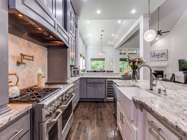 Kitchen featuring range with two ovens, gray cabinetry, a sink, light stone countertops, and recessed lighting | Image 6