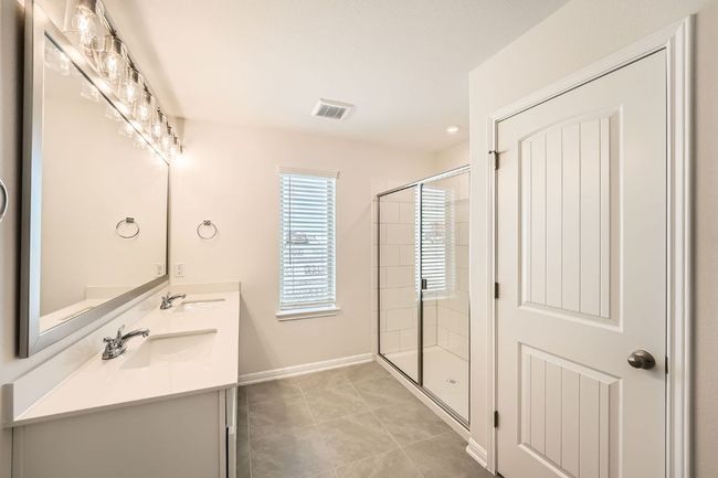 Bathroom with visible vents, double vanity, a stall shower, tile patterned floors, and a sink | Image 16