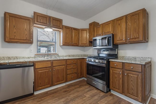 Kitchen featuring dark hardwood / wood-style flooring, sink, light stone countertops, and appliances with stainless steel finishes | Image 20