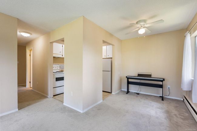 Empty room with baseboard heating, a ceiling fan, light colored carpet, and baseboards | Image 14
