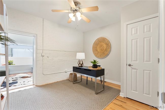 Home office with brick wall, light wood-style flooring, and a ceiling fan | Image 17