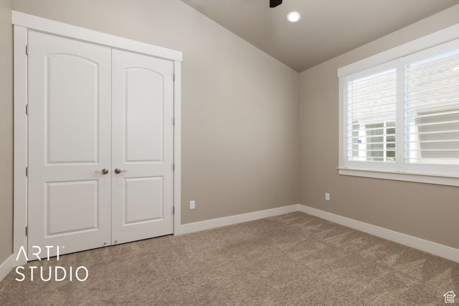 Unfurnished bedroom with vaulted ceiling, carpet flooring, a closet, and recessed lighting | Image 11