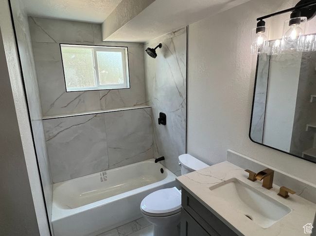 Bathroom featuring vanity, shower / washtub combination, marble finish floors, and a textured wall | Image 22
