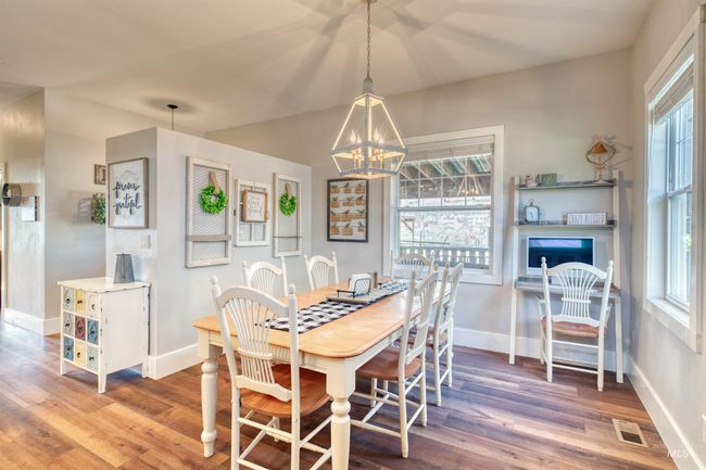 Dining space featuring wood finished floors, a chandelier, and a fireplace | Image 11