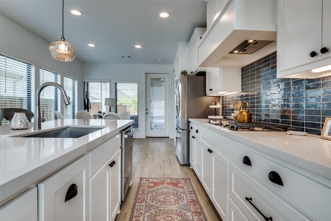 Kitchen featuring stainless steel appliances, custom range hood, decorative backsplash, recessed lighting, and white cabinets | Image 13