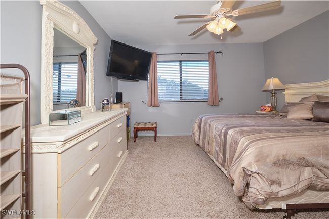 Bedroom featuring multiple windows, a ceiling fan, and light colored carpet | Image 19