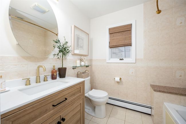 Full bath with tile walls, toilet, baseboard heating, and tile patterned floors | Image 33