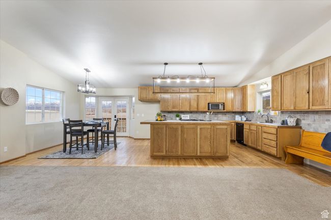 Kitchen with stainless steel microwave, tasteful backsplash, light countertops, and vaulted ceiling | Image 7