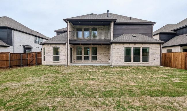 Rear view of house with brick siding, a patio, a fenced backyard, and a balcony | Image 22