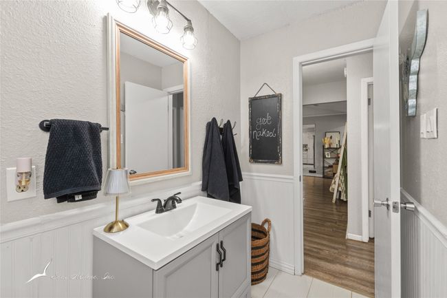 Bathroom featuring a decorative wall, a textured wall, wainscoting, and vanity | Image 20