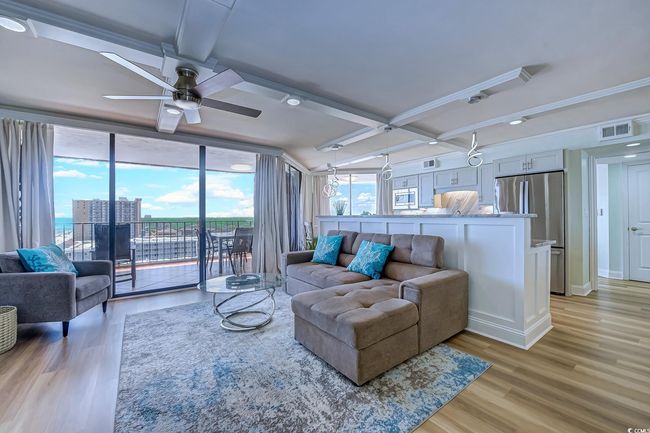 Living room with light hardwood / wood-style flooring, beamed ceiling, coffered ceiling, ceiling fan, and ornamental molding | Image 5