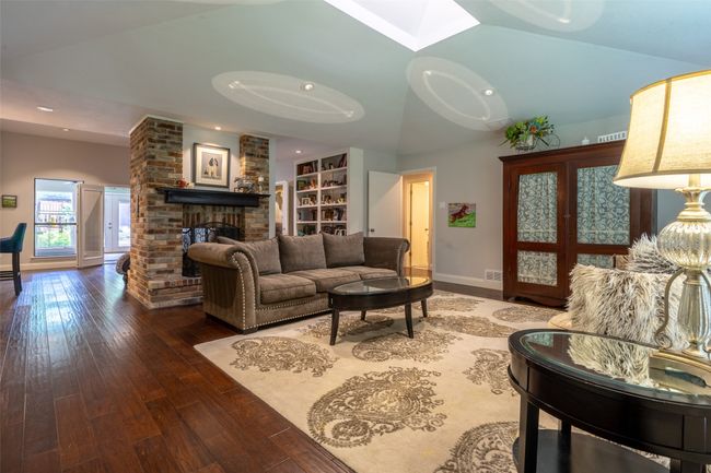 Living area featuring hardwood / wood-style floors, baseboards, a fireplace, vaulted ceiling, and recessed lighting | Image 4
