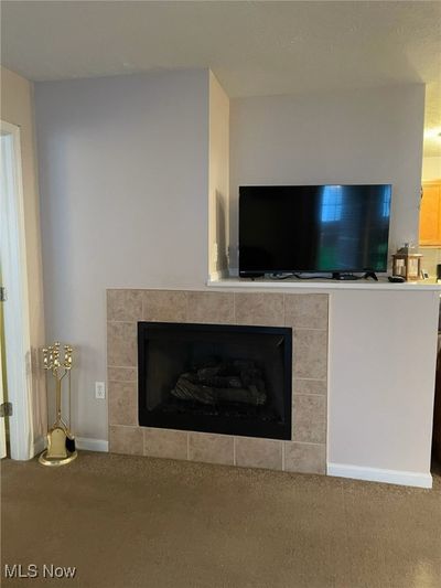 Unfurnished living room featuring a textured ceiling, a chandelier, and dark colored carpet | Image 3